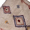 bohemian-moroccan-berber-shag-rug Straight vertical display of ivory Moroccan rug showing three central stacked diamond patterns in red, blue, yellow, and purple.