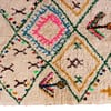 geometric-diamond-moroccan-wool-carpet Top-down view of a vibrant Moroccan area rug with pink, blue, and yellow diamond shapes.