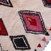 moroccan-boho-rug-with-vibrant-shapes Slight angled front view highlighting thick wool texture and vibrant red, pink, yellow, and green patterns.