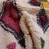 moroccan-diamond-pattern-wool-carpet Middle section detail featuring layered diamond patterns in black, red, and pink.