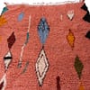 multicolor-moroccan-wool-diamond-rug Handcrafted Moroccan boho carpet with a coral pink base and multicolor diamond motifs.