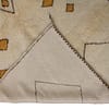 neutral-moroccan-wool-area-rug-with-diamonds Partial side view showing the rug’s soft texture and subtle brown border lines.