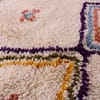 thick-pile-berber-rug-with-tribal-design Close-up of small scattered floral and symbolic motifs on the ivory background.
