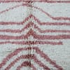 berber-chevron-handwoven-rug A close-up of a brown and regabé wool rug with a distinctive pattern and light pink and cream tones.