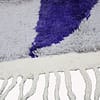 handmade-berber-rug-cream-purple-modern-style close-up displaying the cream tassels and lower purple stripe detail.