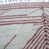moroccan-beni-ourain-rug-white-pink A handwoven Berber wool rug showcasing the skill of traditional Moroccan artisans. Close-up.