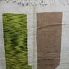 natural-dyed-wool-moroccan-rug Angled display of white Beni Ourain rug with green, brown, and yellow accents.