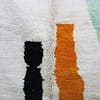 handmade-moroccan-rug-cream-black-orange-pattern.jpg Moroccan rug placed near a wall with full abstract design visible