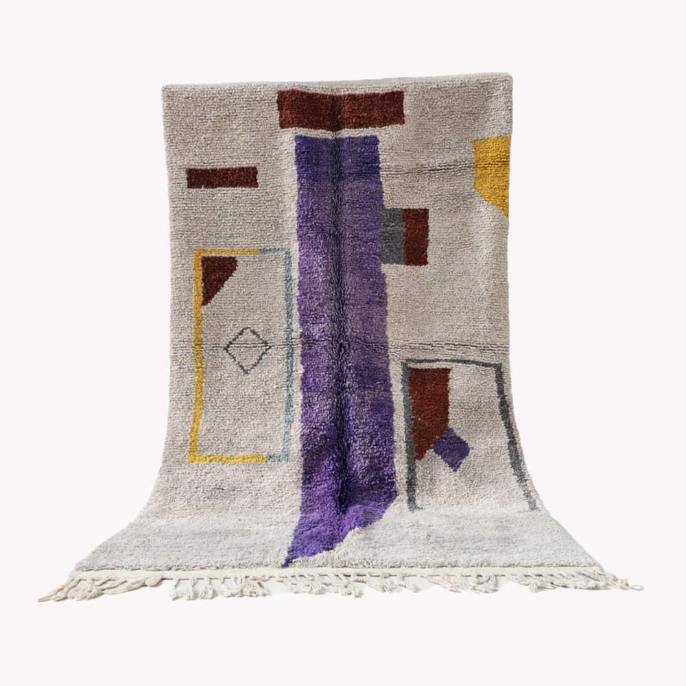 bohemian-modern-wool-carpet-geometric-art Full view of a handmade Moroccan Berber rug with a cream base and purple vertical stripe, displayed upright.