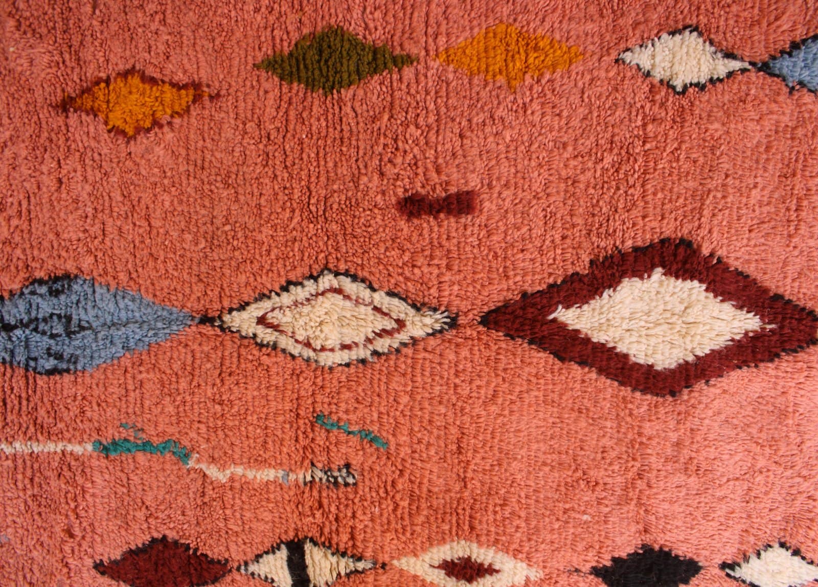 handcrafted-moroccan-boho-carpet Front-facing image of a pink Berber rug with burgundy, blue, and cream diamond accents.