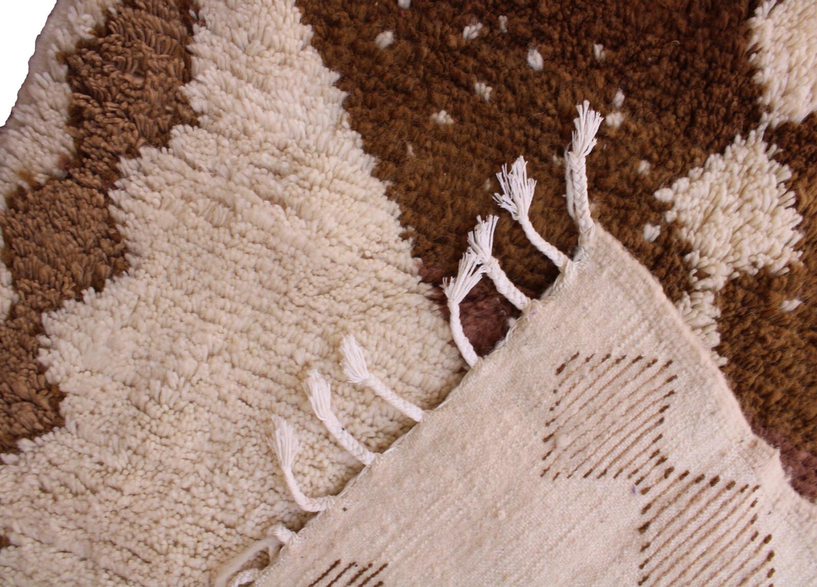 ivory-berber-rug-with-brown-geometric-pattern Bottom section view showing short fringes and handcrafted edge finishing.