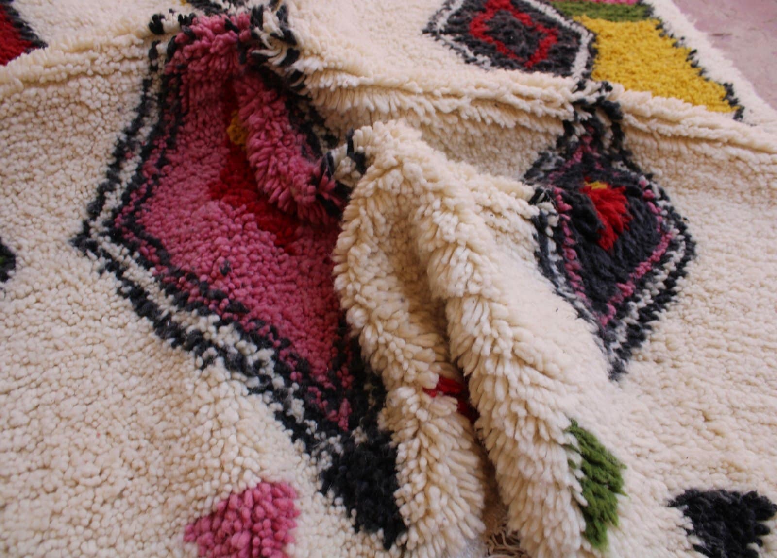 moroccan-diamond-pattern-wool-carpet Middle section detail featuring layered diamond patterns in black, red, and pink.
