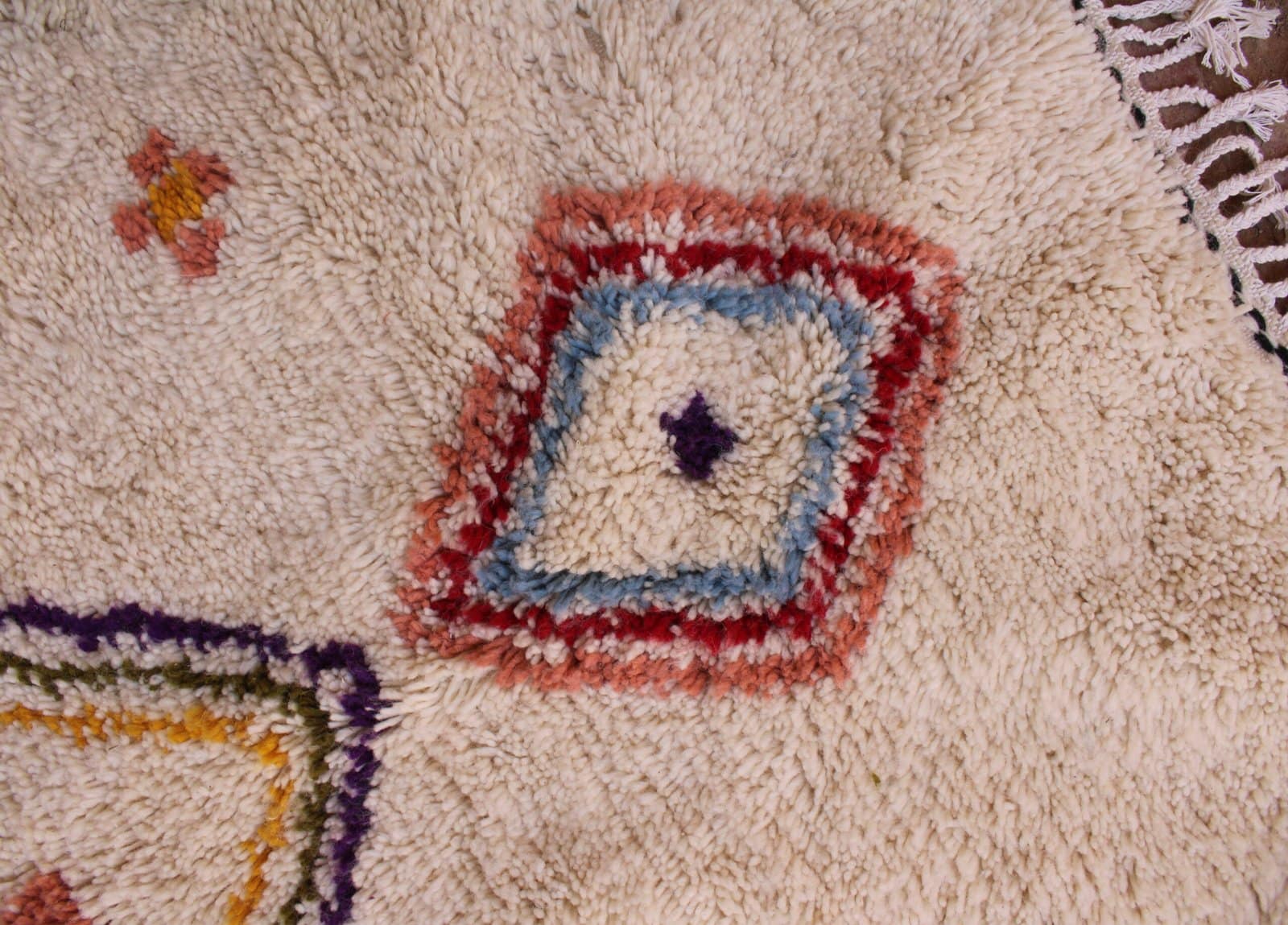 premium-handwoven-berber-rug-with-fringes Side border detail showing vertical arrow-like tribal patterns along the edges.