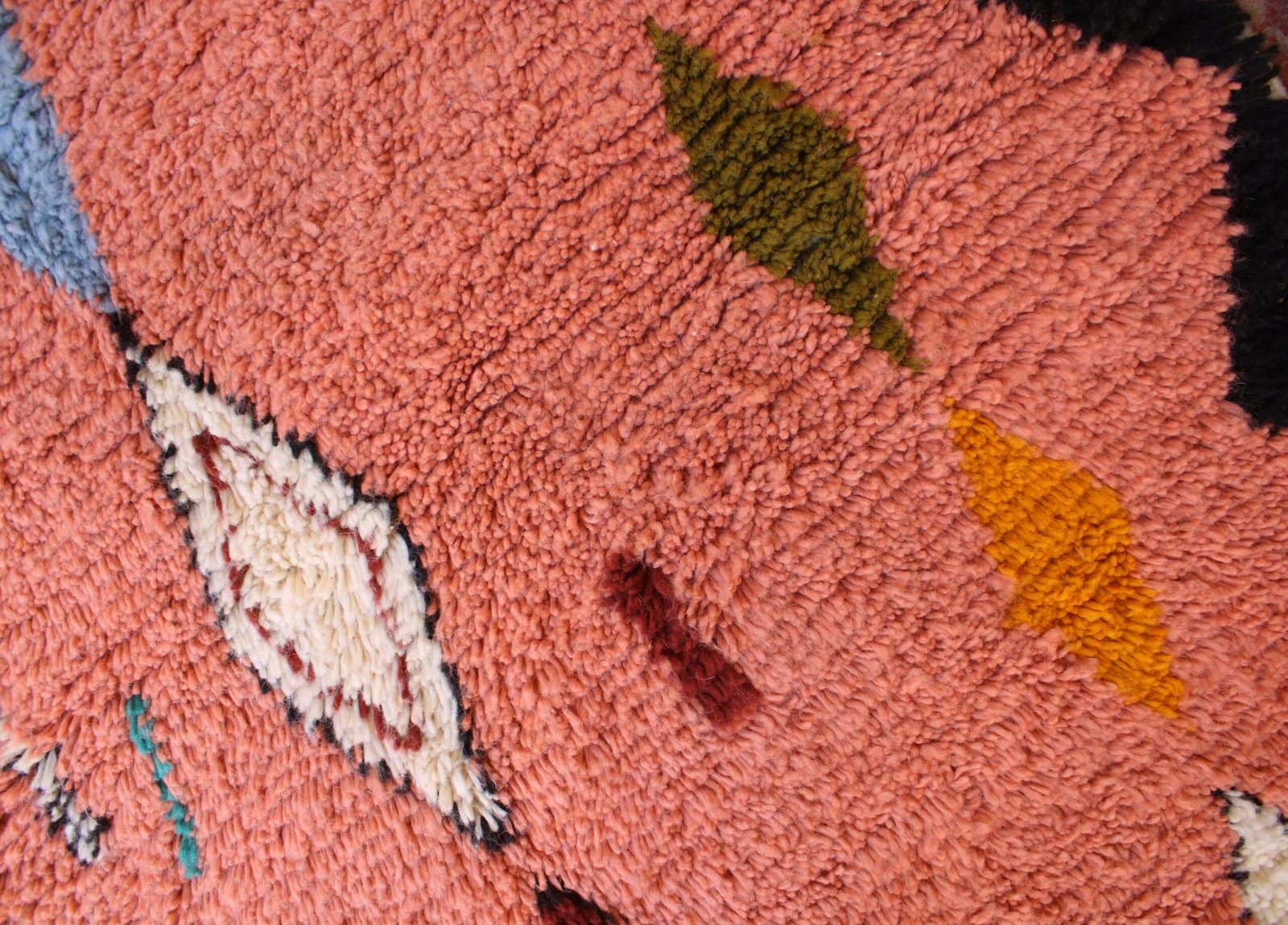 statement-moroccan-berber-pink-rug Close-up of plush wool texture and vibrant geometric shapes on a bohemian Moroccan carpet.