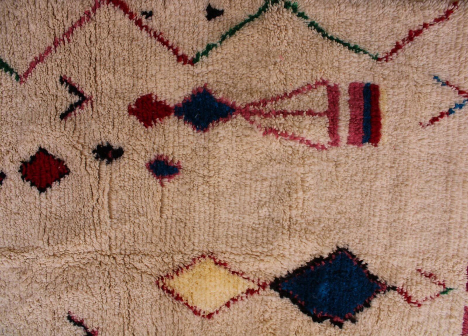 thick-pile-berber-moroccan-rug Close-up detail of colorful diamond shapes woven into the soft ivory background.