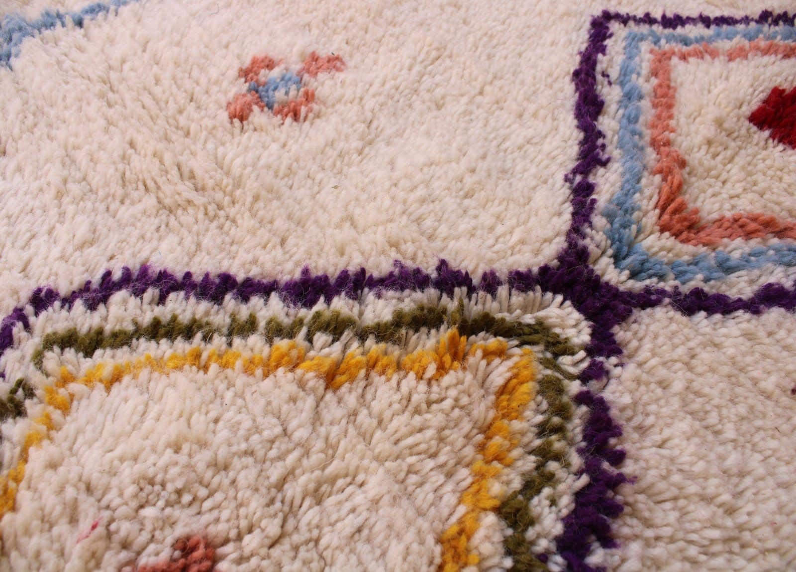 thick-pile-berber-rug-with-tribal-design Close-up of small scattered floral and symbolic motifs on the ivory background.