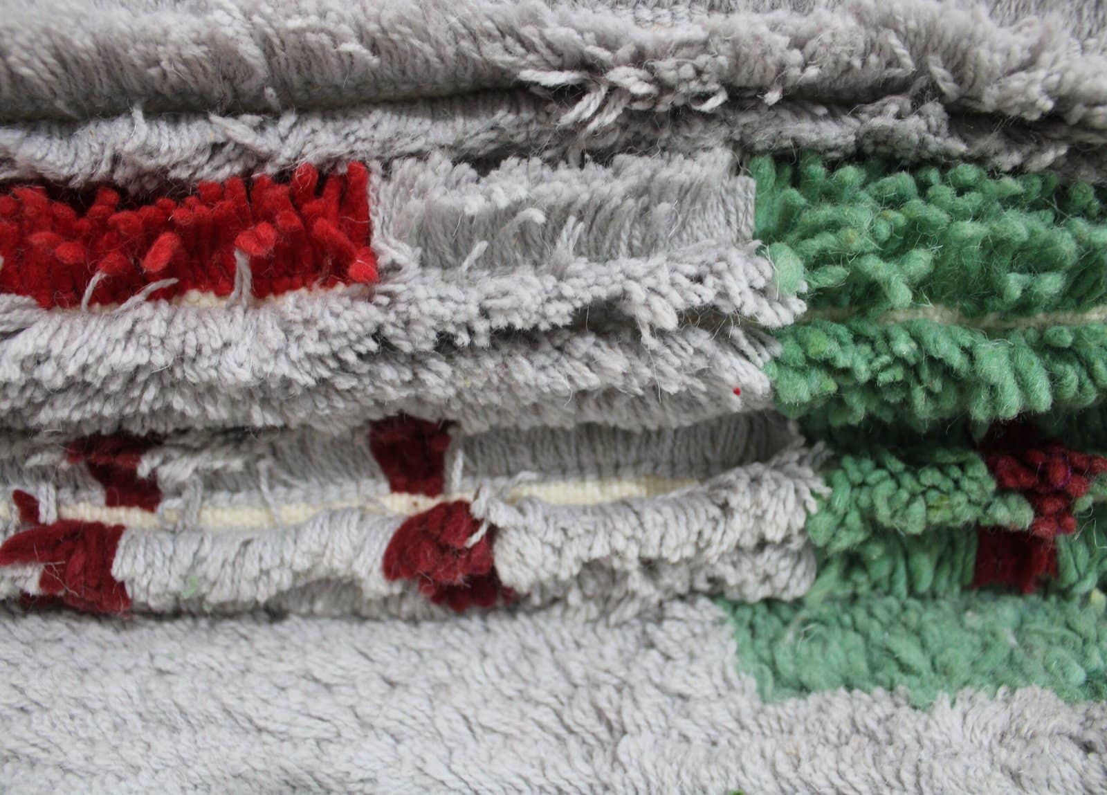 abstract-moroccan-rug-green-red-geometric Slight side perspective of the rug emphasizing the depth and handwoven craftsmanship.