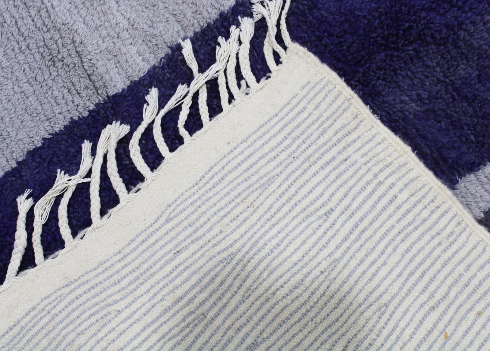abstract-moroccan-rug-purple-geometric-design Close-up of the Moroccan wool rug highlighting the thick pile texture and geometric brown and yellow accents.