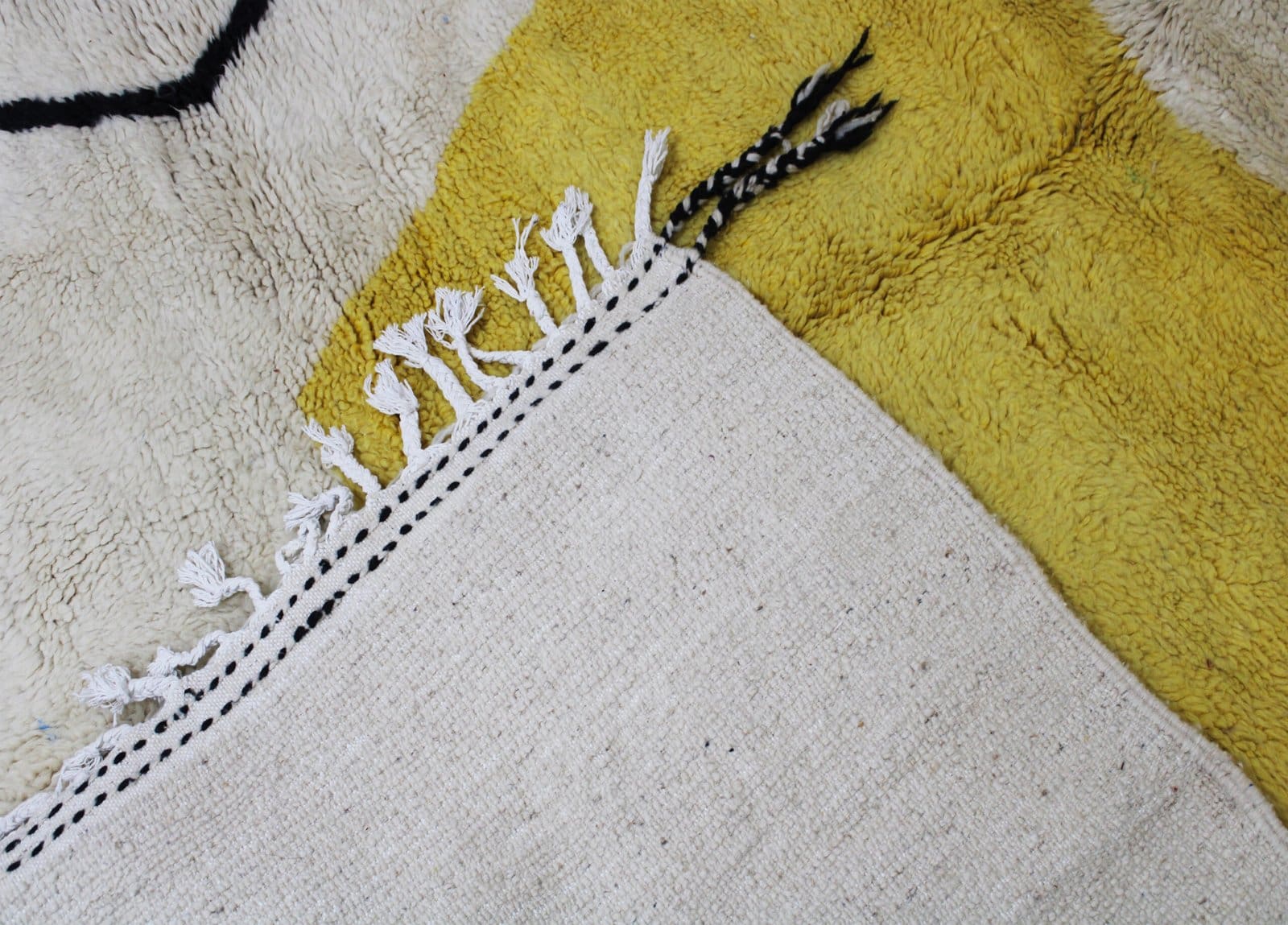 artisan-berber-area-rug-cream-base Side angle of handmade Moroccan Berber rug highlighting thickness and wool texture.