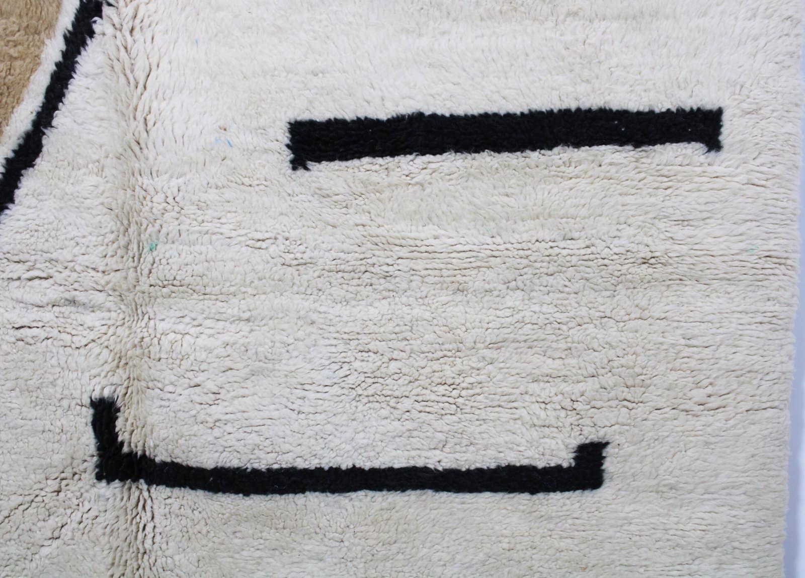 atlas-mountains-handwoven-rug-abstract Macro shot of soft cream Moroccan rug with abstract yellow and brown patterns.