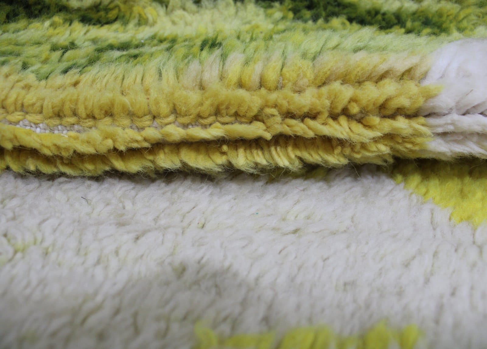 black-and-white-berber-rug Close-up of Beni Ourain rug texture showing white wool and green, brown, and yellow details.
