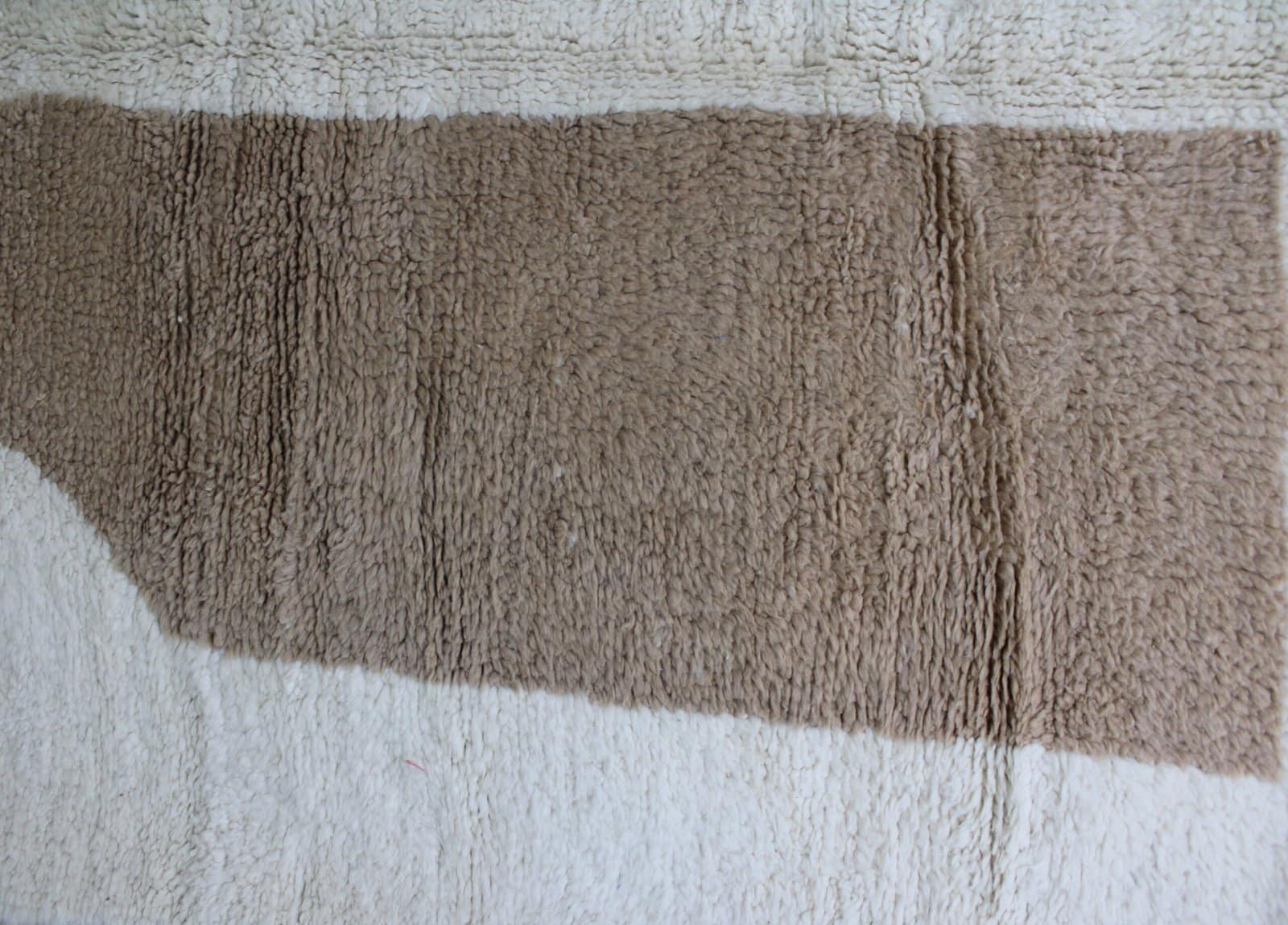 bohemian-moroccan-area-rug Folded Moroccan Beni Ourain rug showing white base and colorful geometric design.