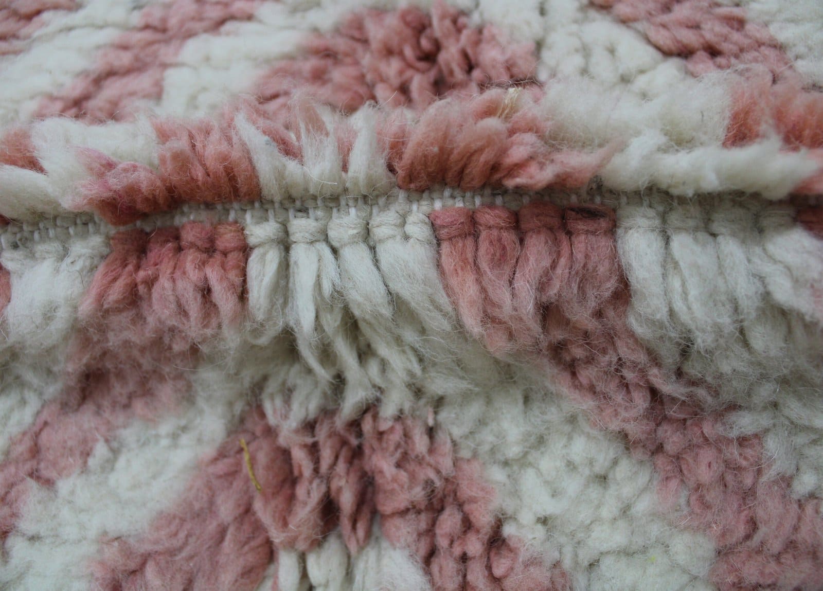 cozy-living-room-moroccan-rug White and pink Berber rug with soft wool texture and fringe detailing.