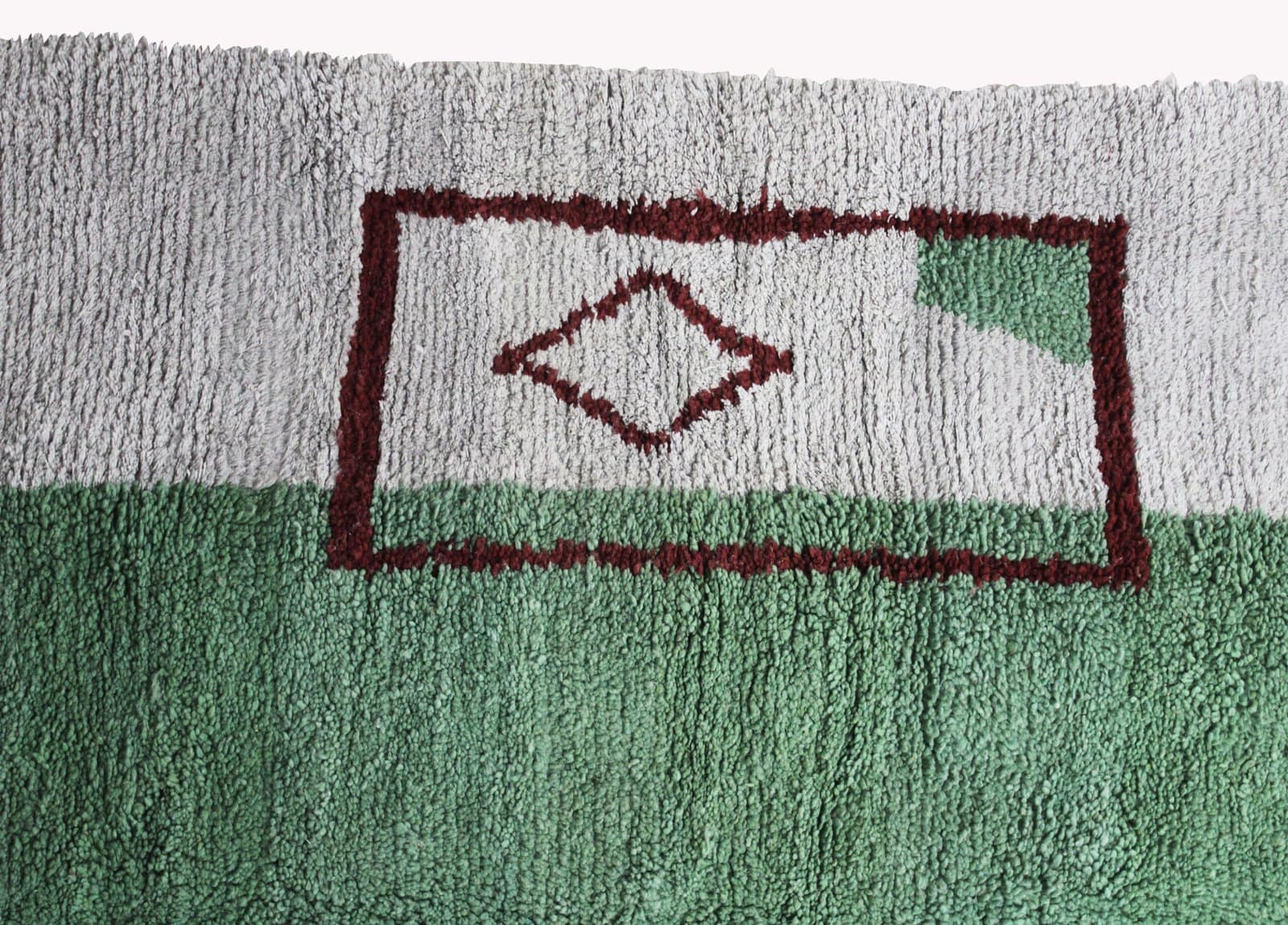 luxury-berber-carpet-green-center-design Side angle view of the handmade rug displaying its thickness and soft pile texture.