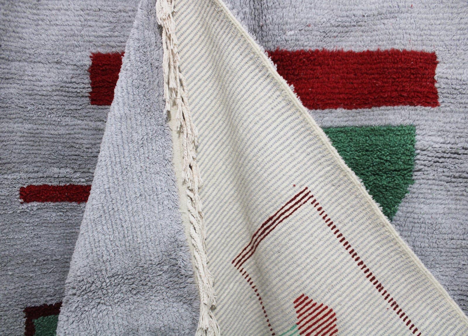 modern-moroccan-area-rug-red-accents Detailed close-up of the rug’s lower section focusing on the woven texture and tassels.