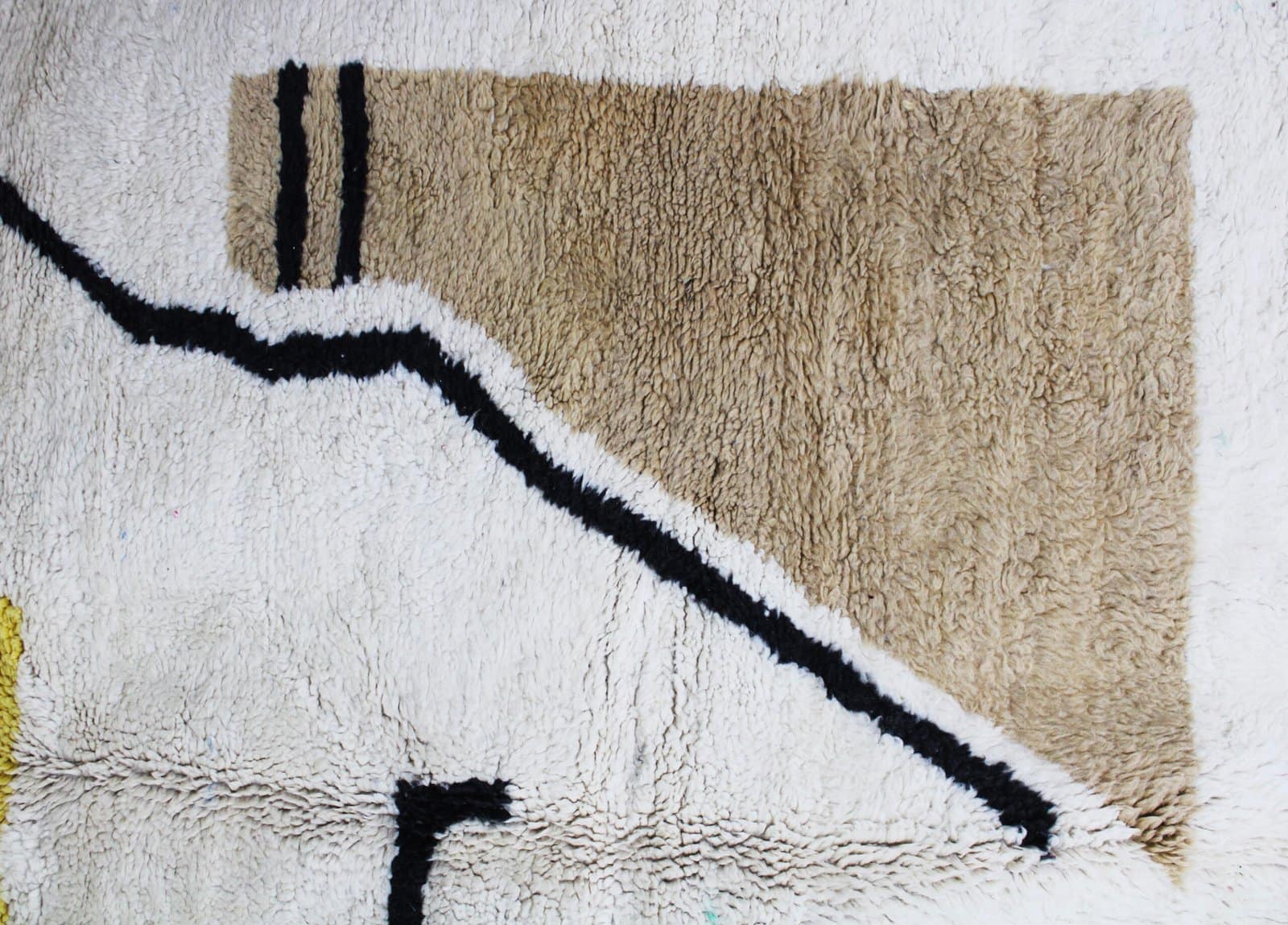 modern-moroccan-rug-yellow-brown-black Detailed view of handwoven Berber rug with black lines and mustard yellow design.