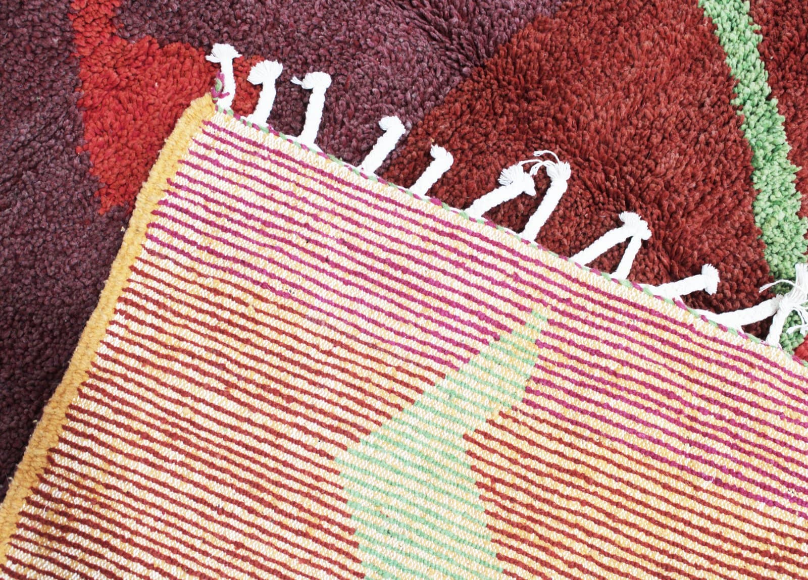 moroccan-abstract-rug-handmade-wool Bottom section close-up displaying the pink border and cream tassels of the handmade rug.