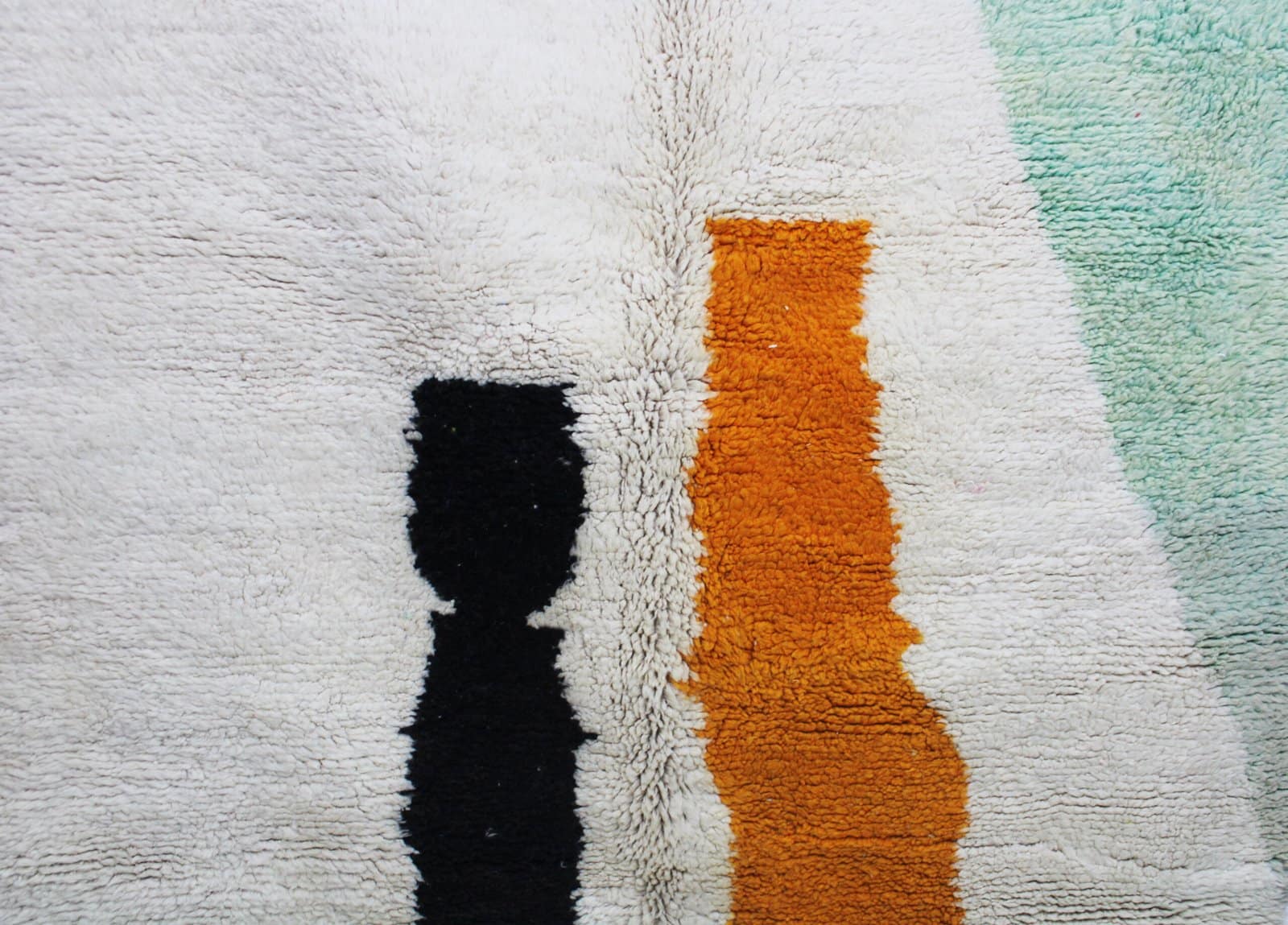 handmade-moroccan-rug-cream-black-orange-pattern.jpg Moroccan rug placed near a wall with full abstract design visible