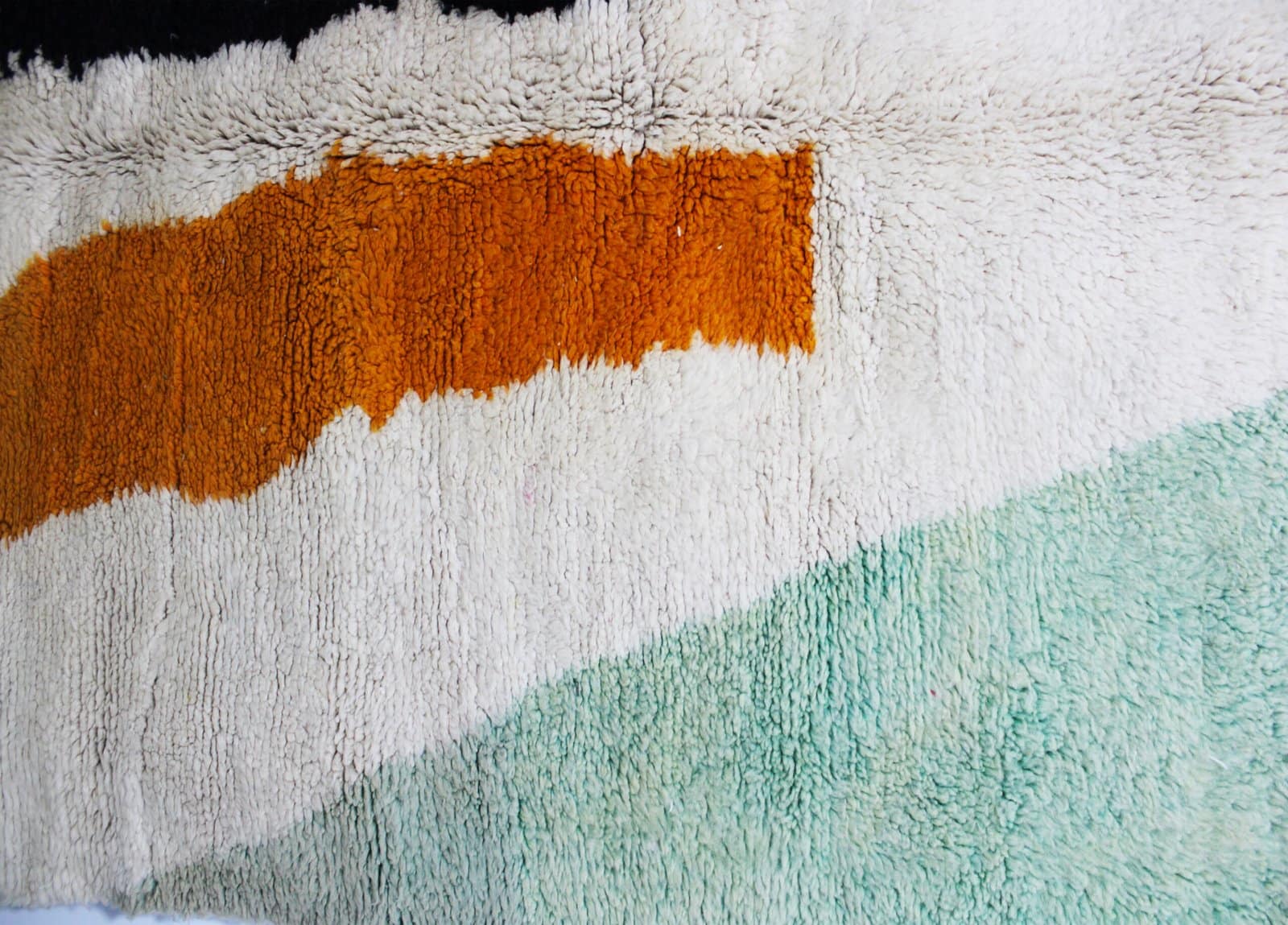 moroccan-berber-rug-cream-base-geometric-design.jpg Side angle view of Moroccan rug highlighting thickness and wool texture